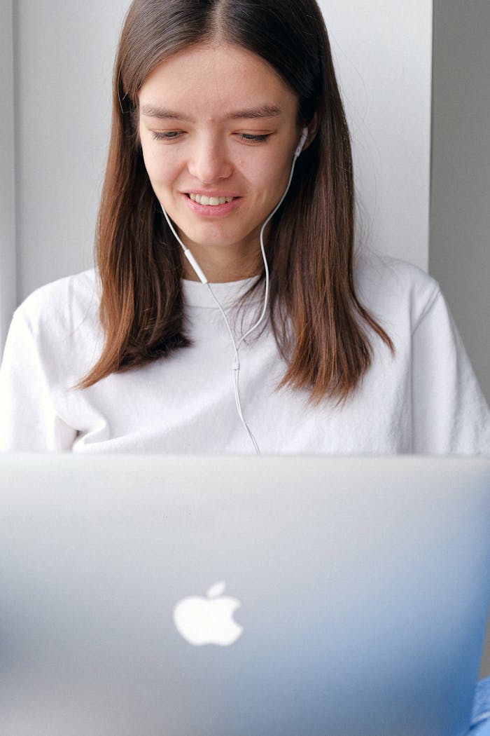 Young woman using a laptop at home, wearing earphones. Ideal for work from home and freelance themes.